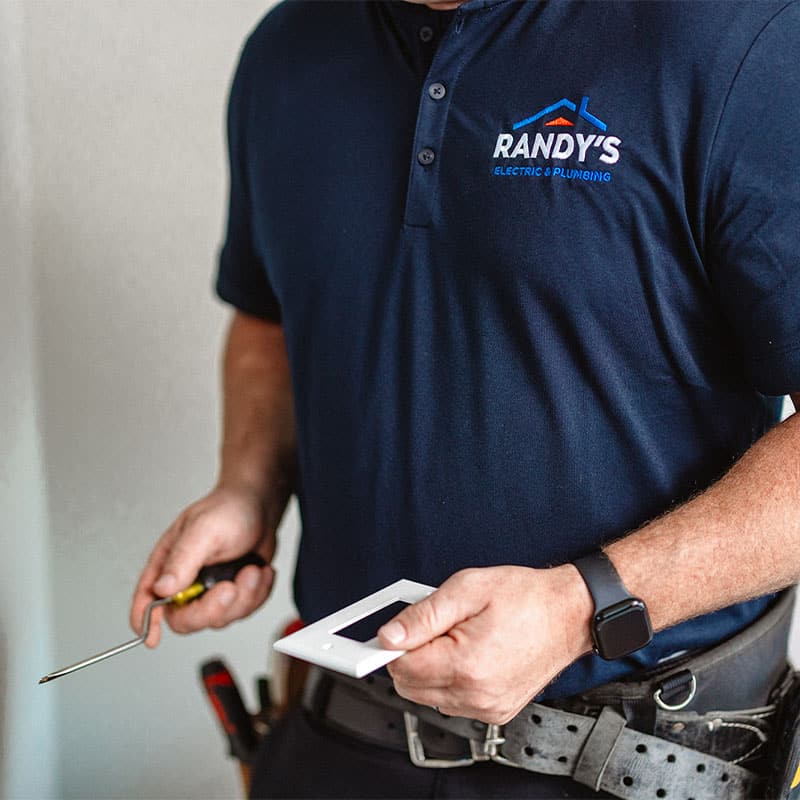 Randy from Randy's Electric & Plumbing holding a screwdriver and light switch cover.